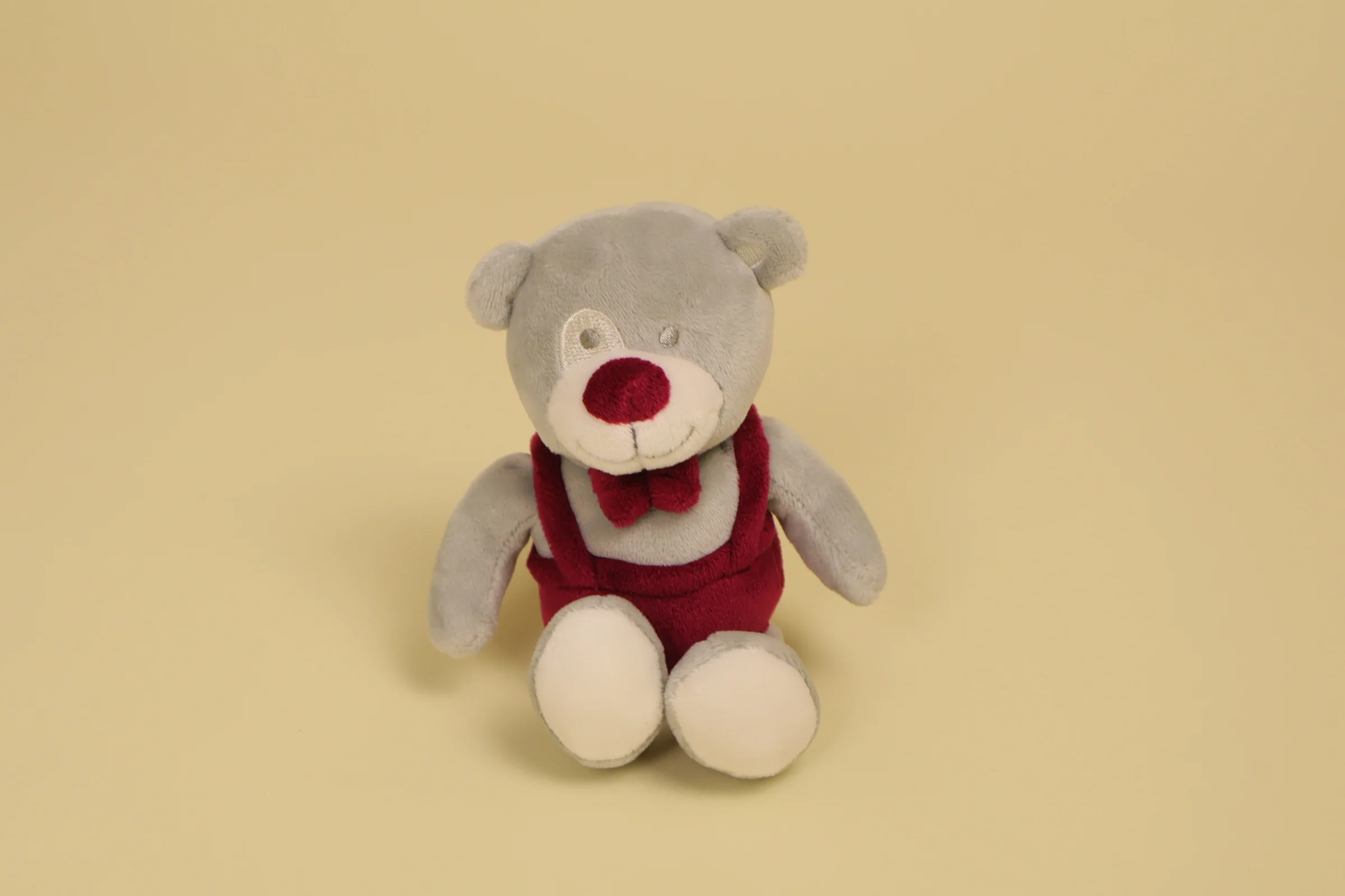 Mini doudou ours gris 16 cm avec salopette et nœud papillon bordeaux marque Trois Kilos Sept