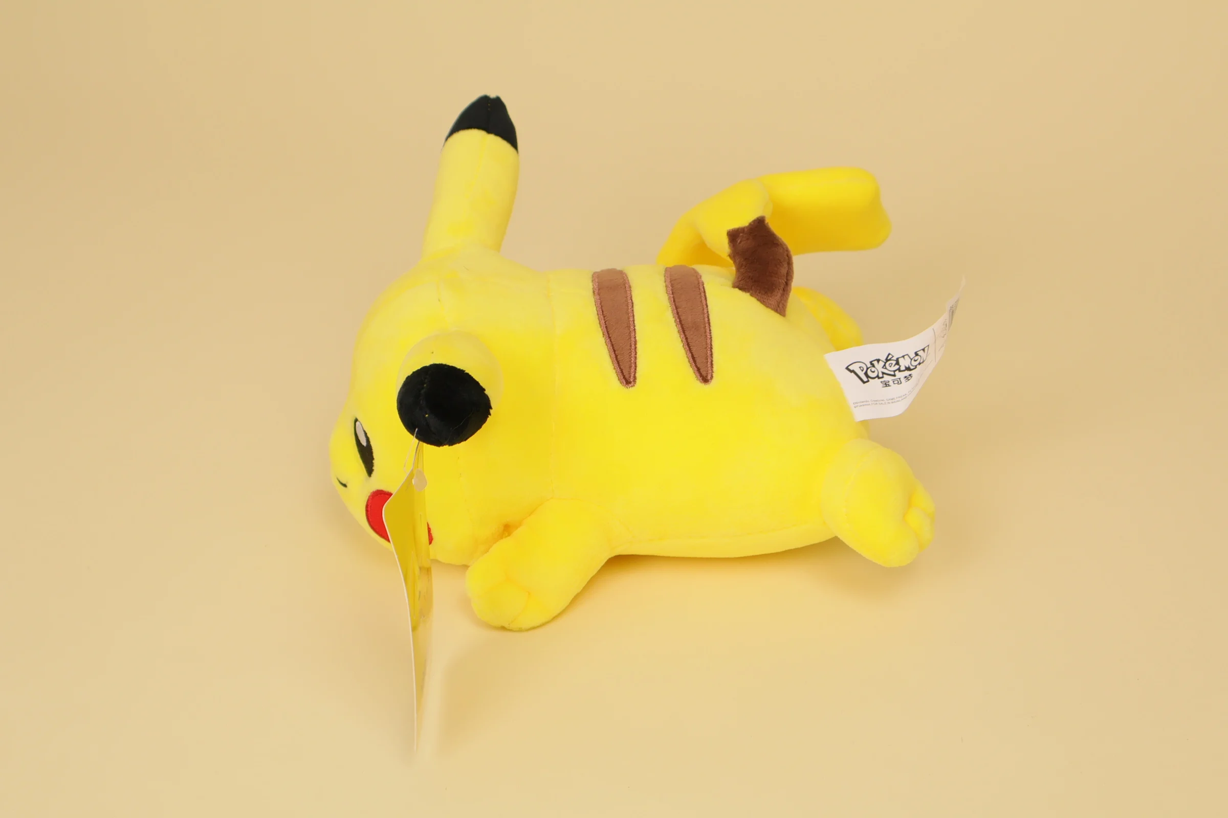 profil Peluche Pokémon Pikachu allongé position jeu 20 cm marque Nintendo doudou jaune doux