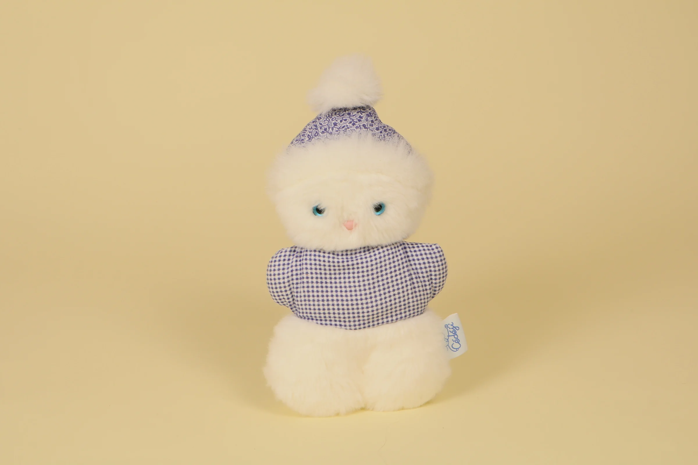 Peluche chat blanc Cedeji 24 cm avec bonnet à pompon et vêtement à carreaux bleus