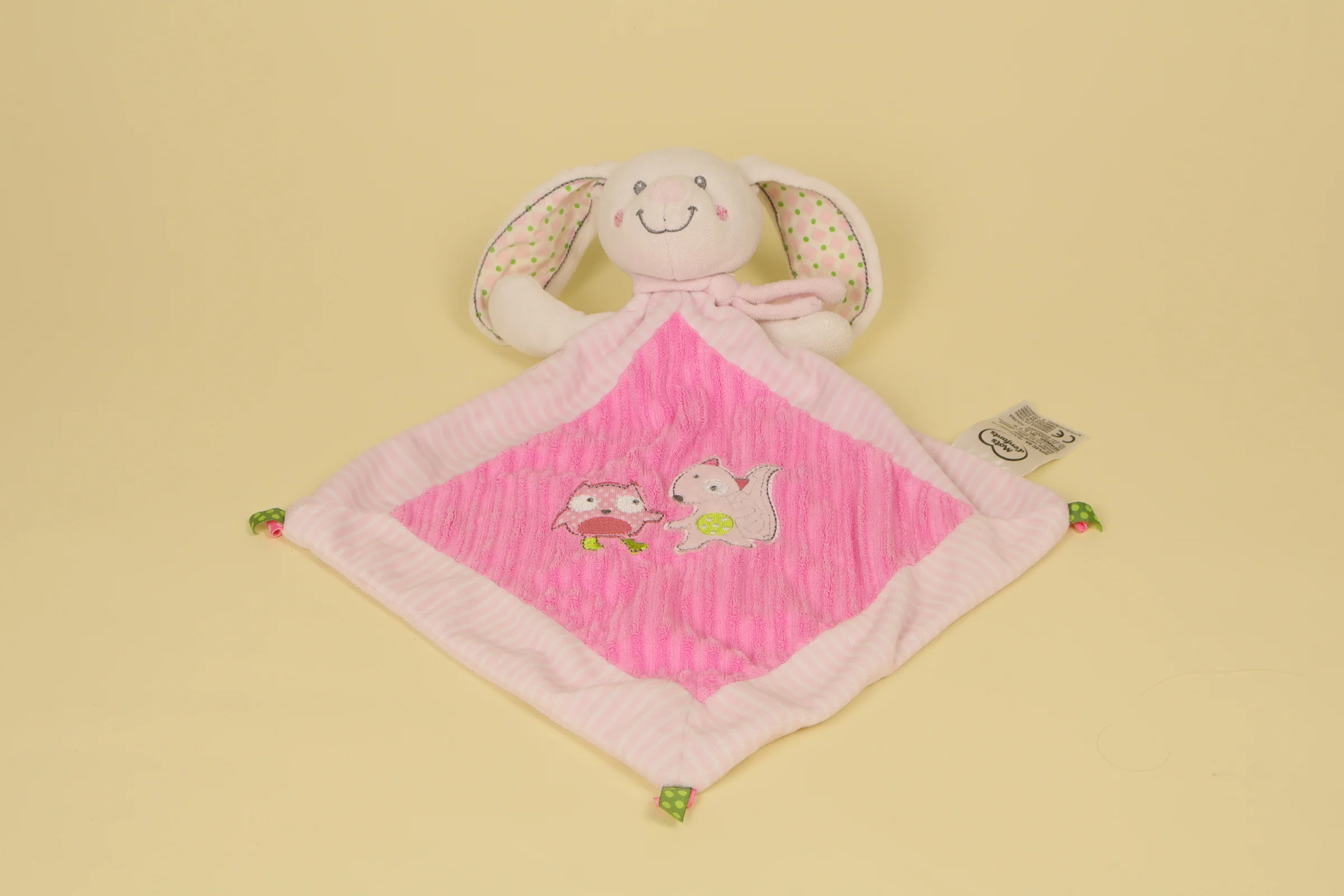 Doudou plat lapin rose en forme de losange avec broderies d'un hibou et d'un écureuil sur le corps de la marque Mots d'Enfants