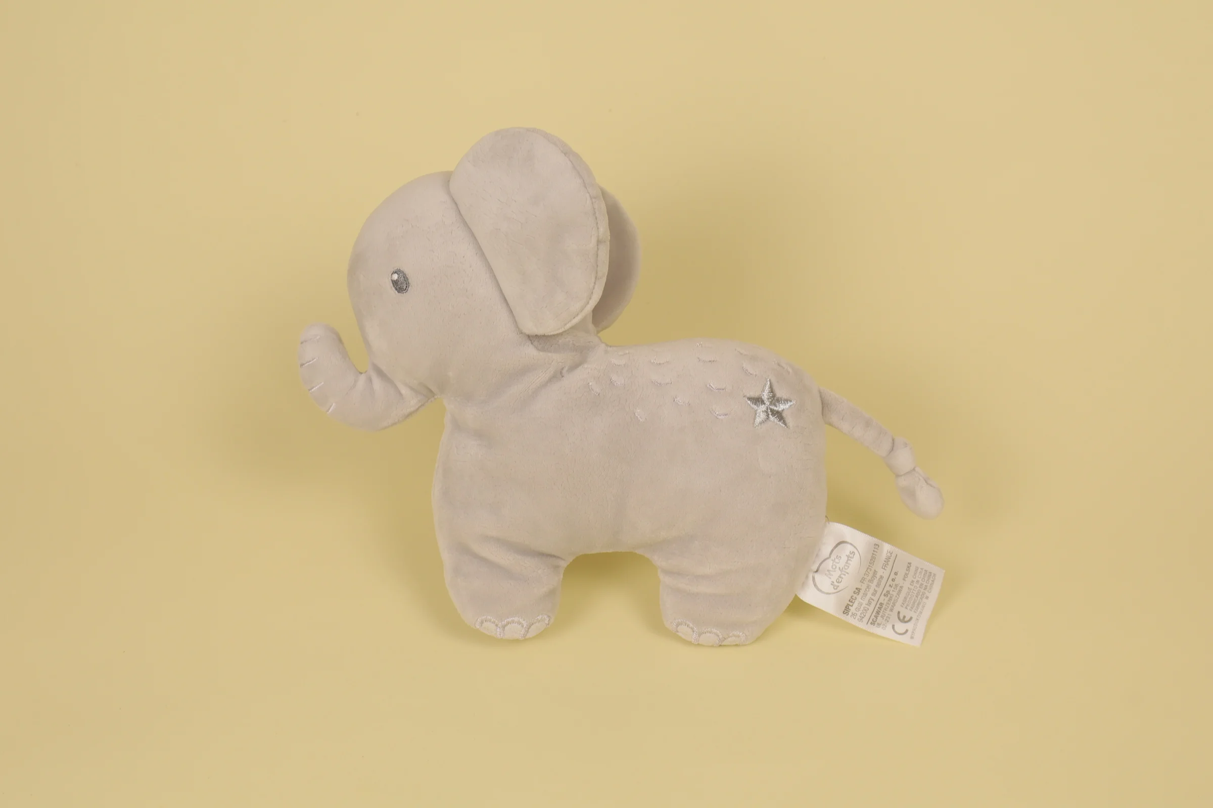 Doudou semi-plat éléphant de couleur gris avec tête en peluche et détails texturés de couleur argenté marque Mots d'Enfants