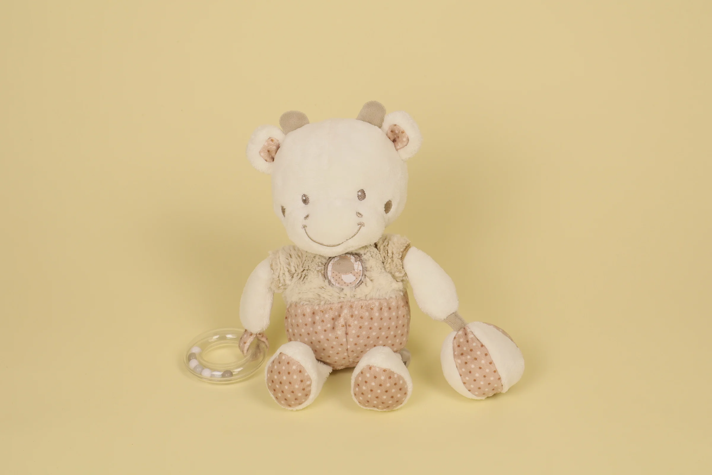 Doudou peluche vache d'activité blanc marron et beige de 25 cm avec petite balle en tissu et anneau de billes en plastique transparent marque Mots d'Enfants