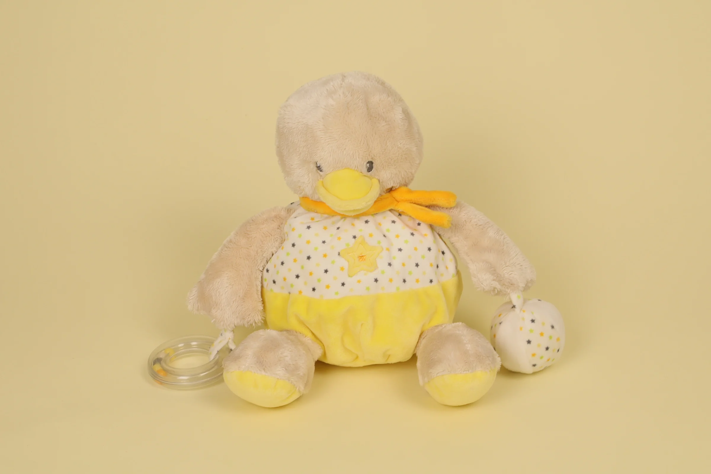 Doudou peluche canard d'activité beige et jaune avec anneau de dentition transparent à billes et balle grelot marque Mots d'Enfants