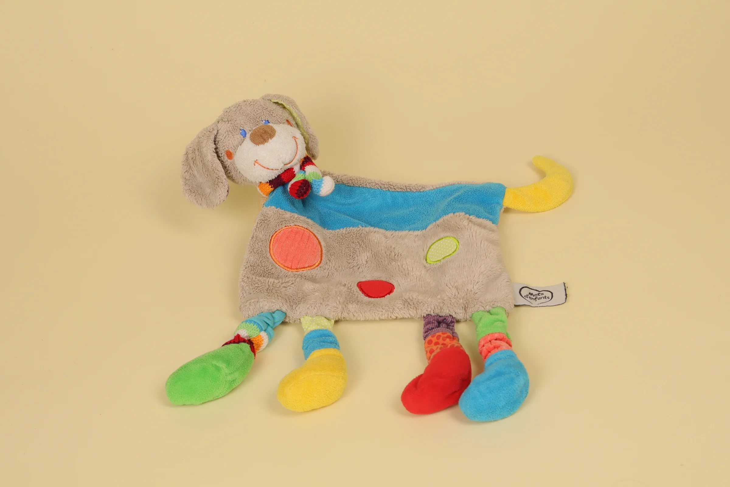 Doudou plat chien gris de forme mouchoir avec motifs de ronds brodés multicolores et petite écharpe rayée marque Mots d'Enfants