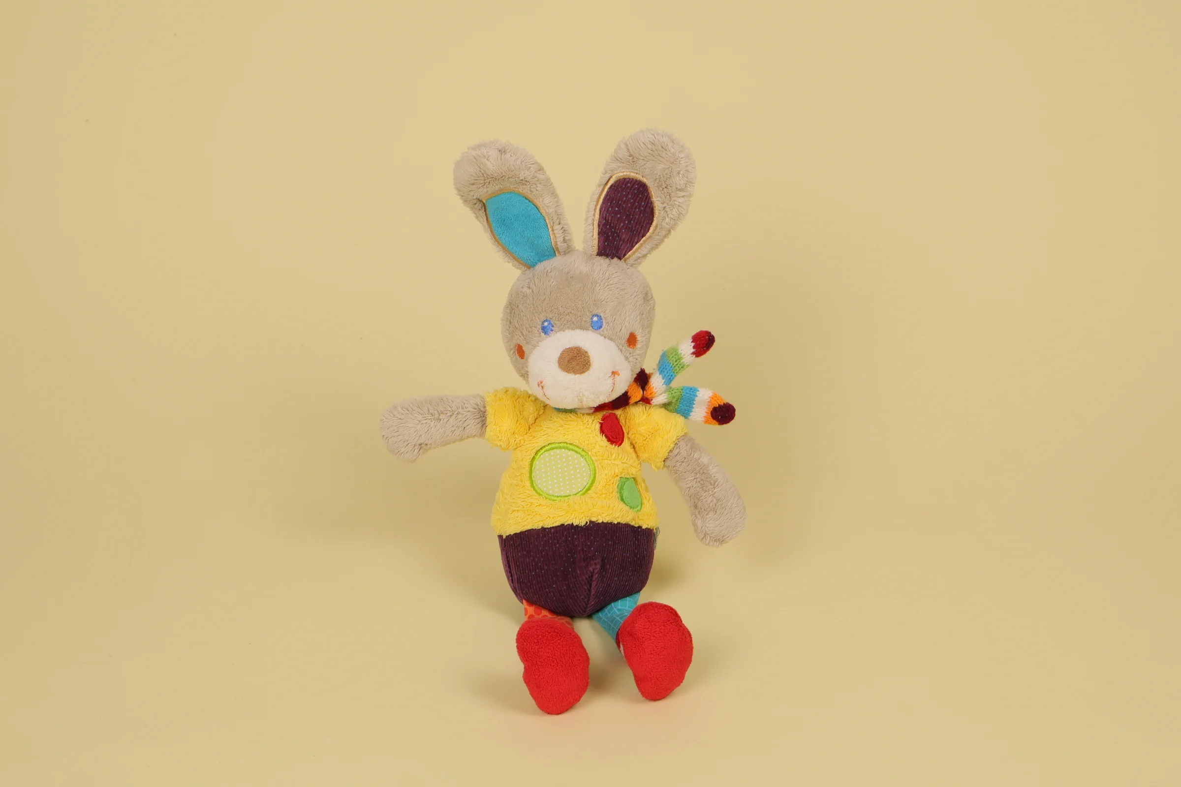 Doudou lapin beige et multicolore avec ronds brodés vert et rouge et écharpe tricotée rayée marque Mots d'Enfants 29 cm