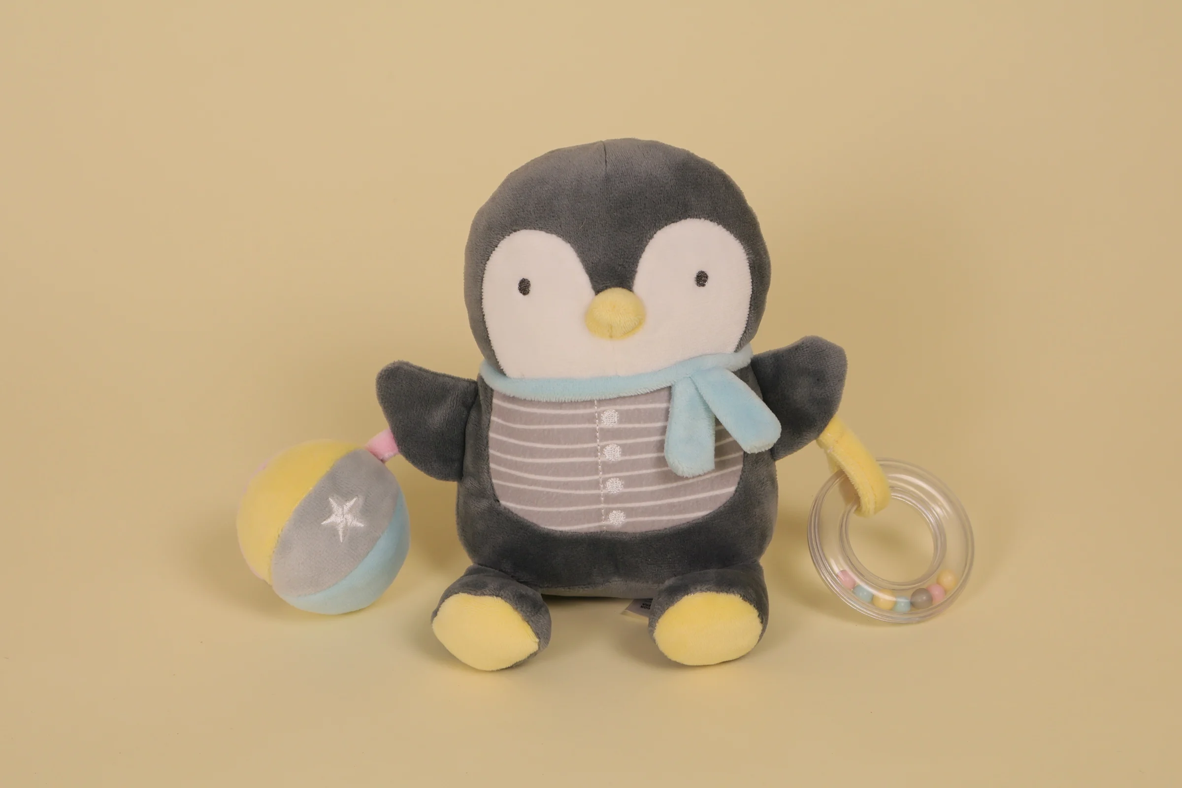 Doudou peluche pingouin d'activité gris bleu et jaune avec anneau de dentition transparent à billes et balle grelot marque Mots d'Enfants