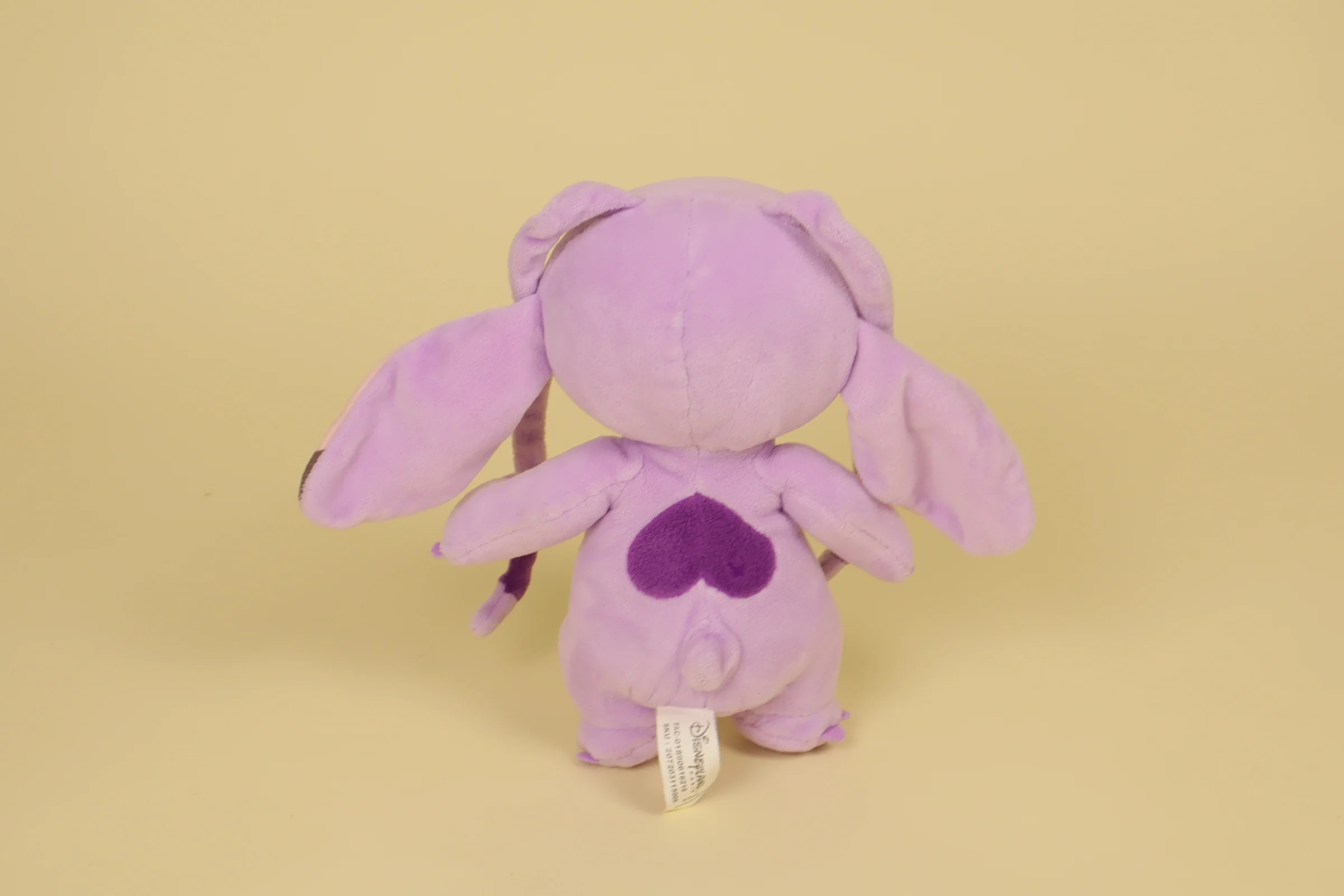 dos Peluche Angel rose et violet clair debout avec petit cœur blanc brodé sur le ventre mesurant 21 cm de la marque Disneyland Paris