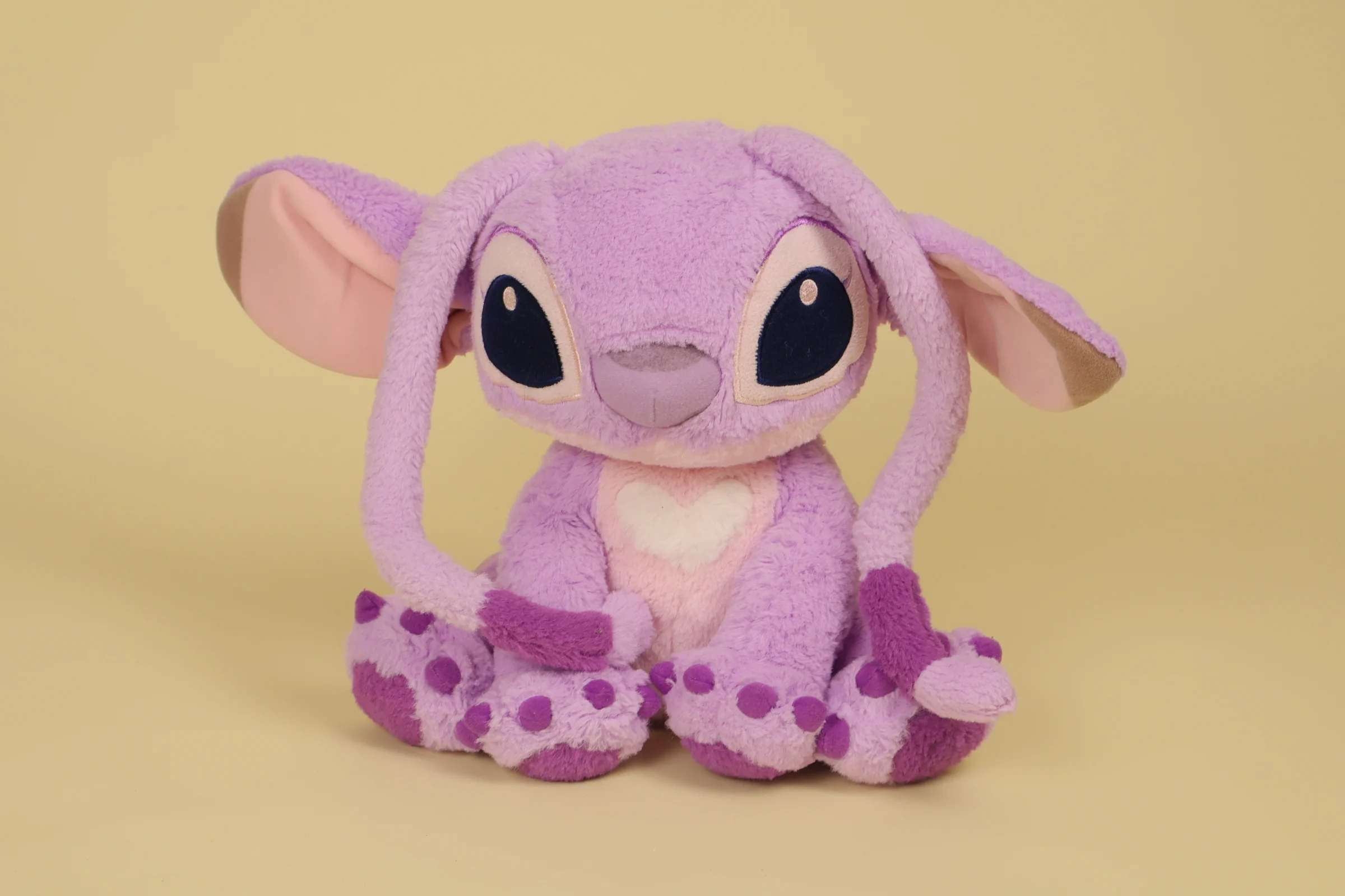 Peluche Angel rose et mauve de 25 cm avec antennes souples sur l'avant et cœur brodé sur la poitrine marque Disneyland Paris