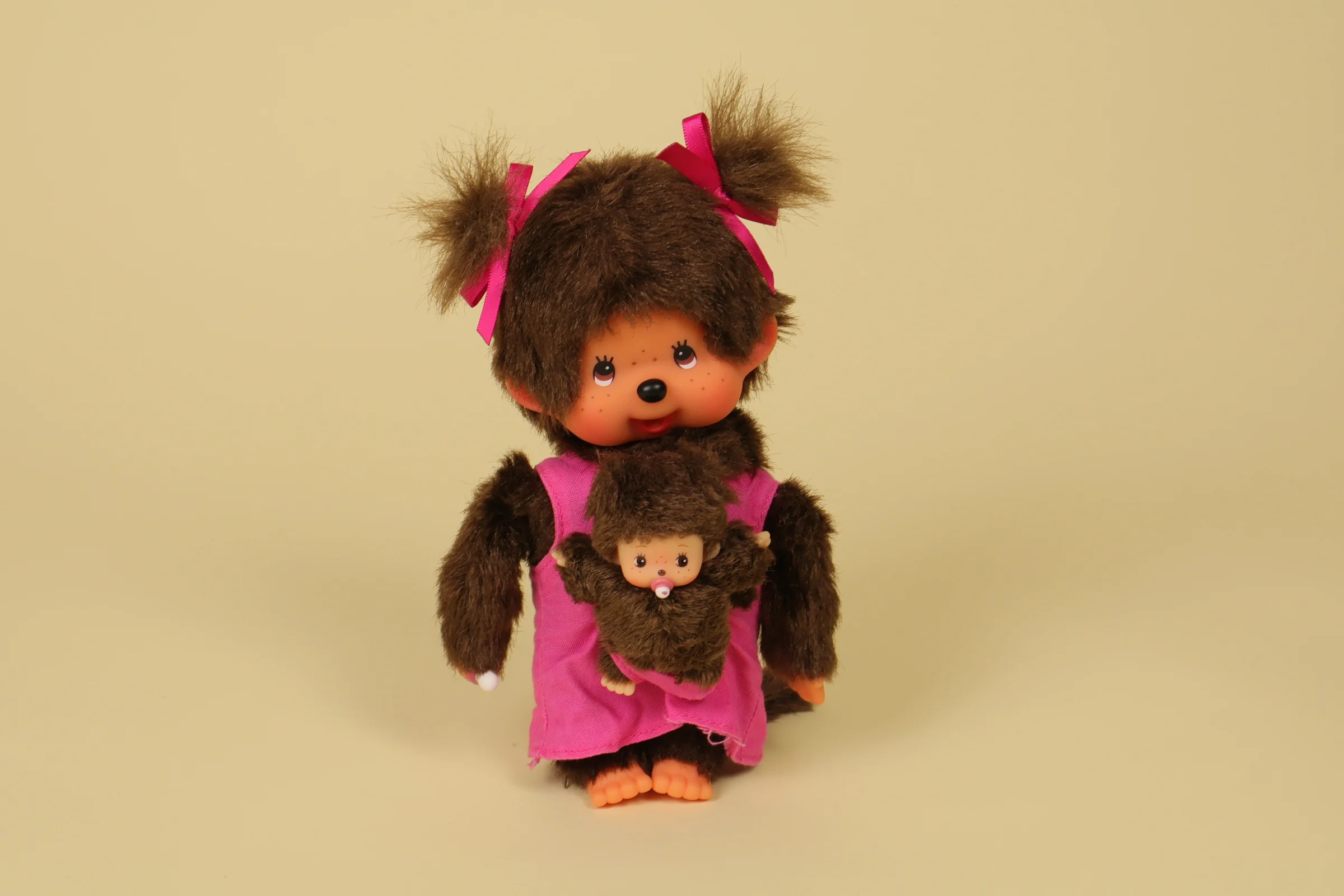 Peluche Kiki Monchhichi de 19 cm portant une robe rose et son bébé sur le devant de la marque Sekiguchi