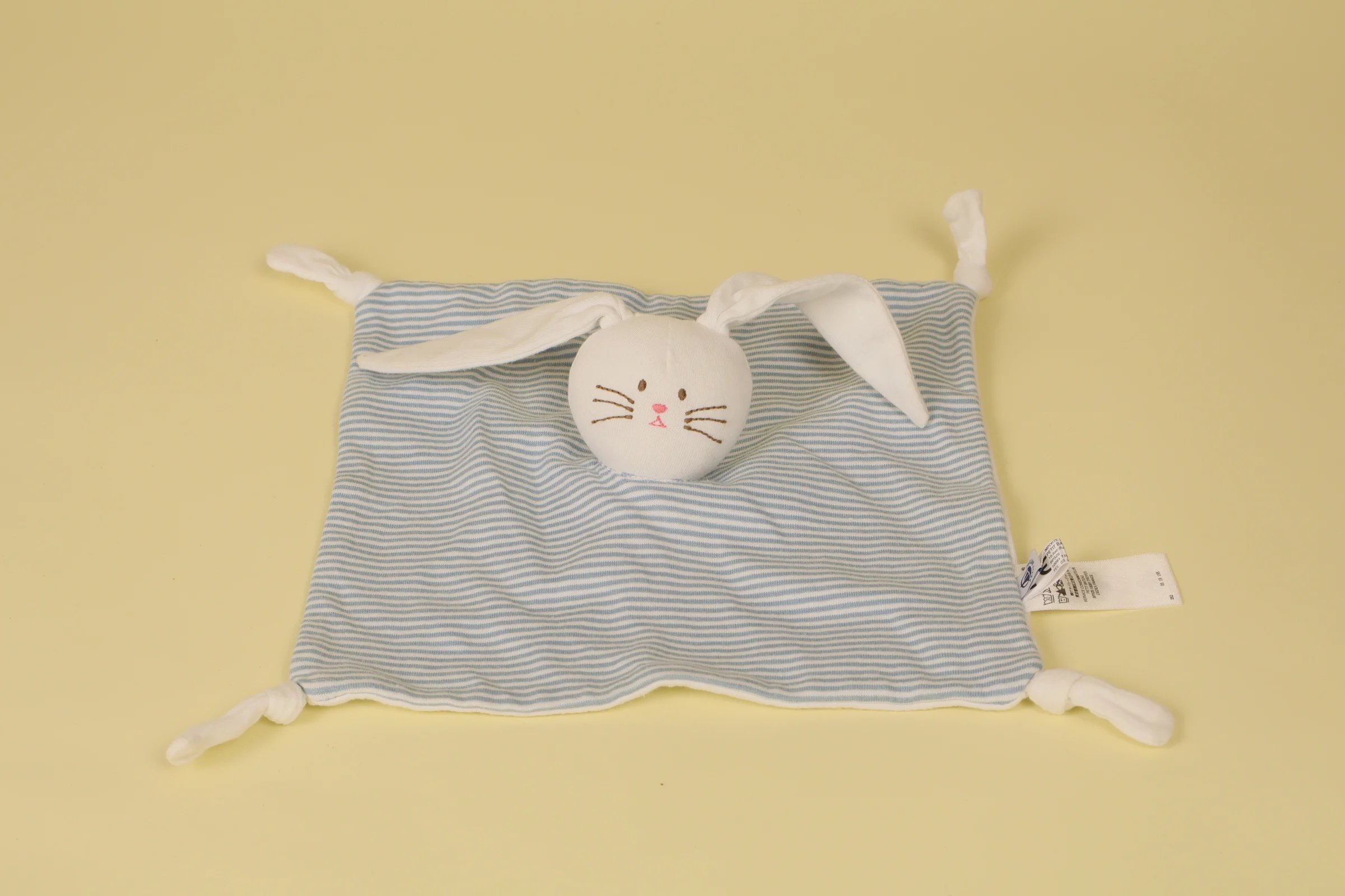 Doudou plat lapin blanc à rayures bleues emblématiques de la marque Petit Bateau