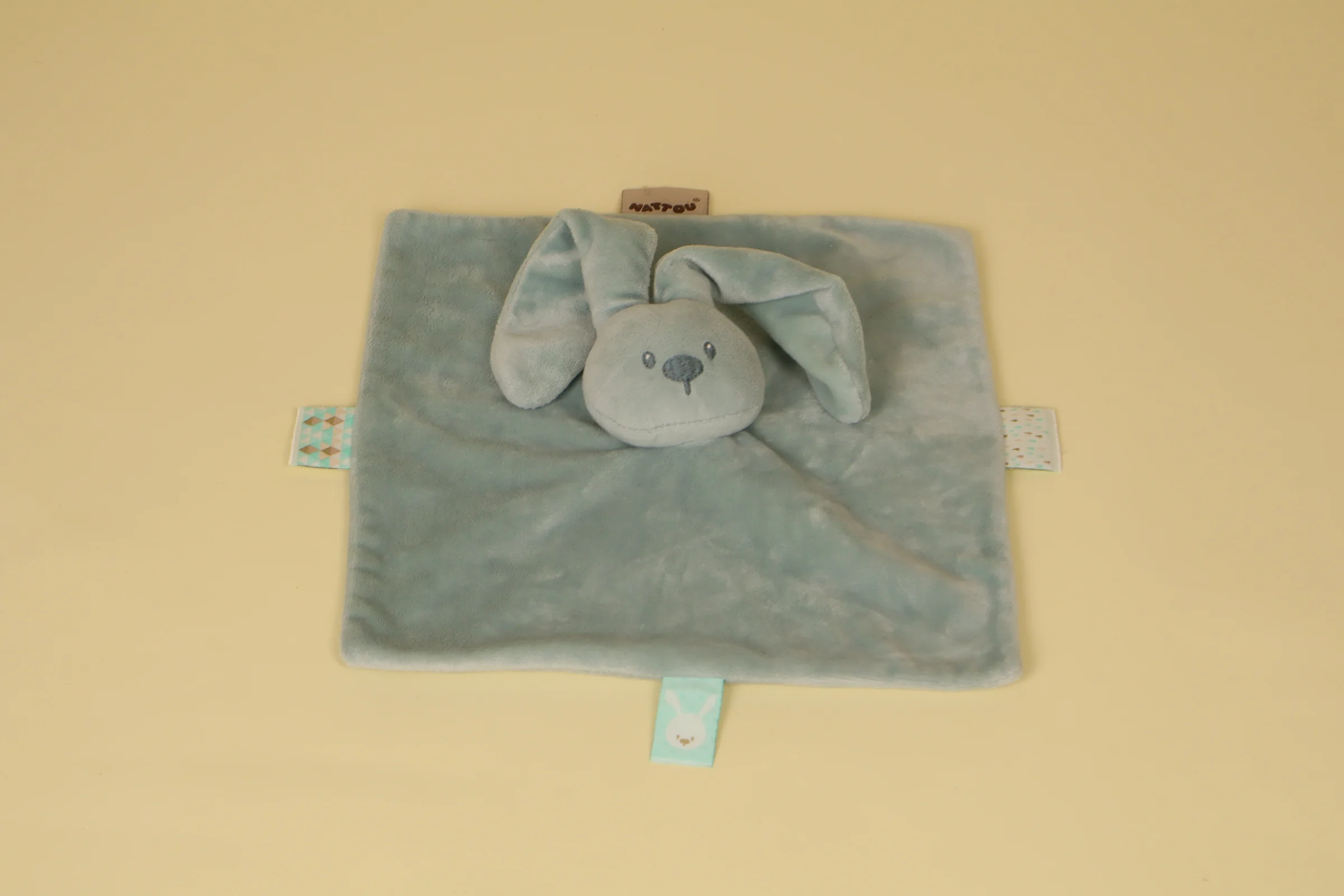 Doudou plat triangle lapin bleu fonce avec attache tetine scratch marque Nattou