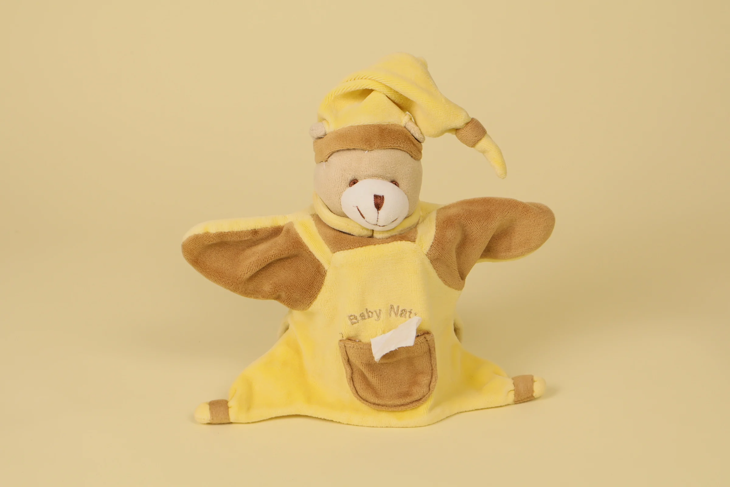 Doudou marionnette ours marron et jaune avec poche ventrale et bonnet de nuit de la marque Baby Nat