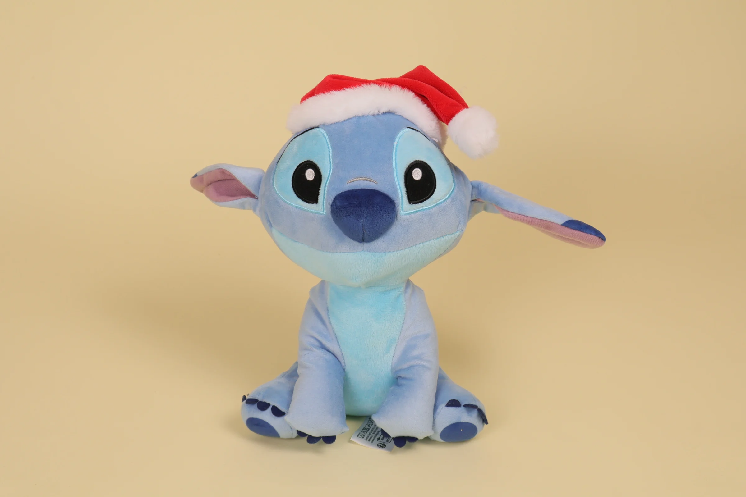 Peluche Stitch bleu de 25 cm portant un bonnet de Noël rouge et blanc de la marque Simba Toys Disney